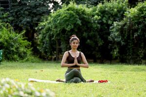 linda sexy dama sentado en estera con cruzado piernas manos en oración meditando foto