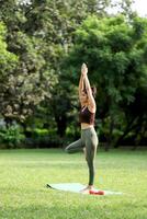 Amazing Hot Woman Standing In Tree Pose On Mat With Red Dumbbells photo