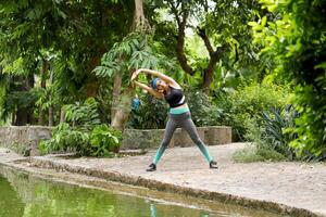 Female Stretching Hands Up Doing Exercise In Park photo