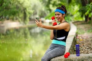 Athletic Female Showing Dumbbell On Mobile Phone photo