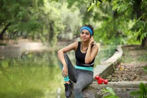 sexy indio modelo escuchando música con auriculares en parque foto