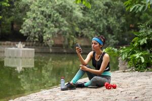 Beautiful Young Lady Holding Mobile Phone In Hand After Exercise photo