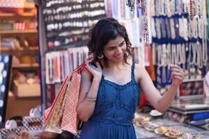 Slim Girl Looking At Bangle While Holding Shopping Bag In Hand photo