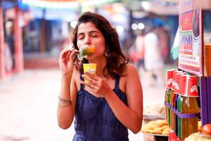 maravilloso dama comiendo hielo Gola en desechable taza foto