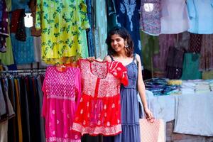 Hot And Sexy Woman Displaying Red Colour Lakhnavi Top In Hand While Looking At Camera photo