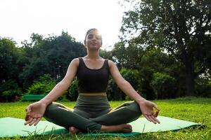 Sweet Young Model In Lotus Pose Sitting On Green Grass In Park photo