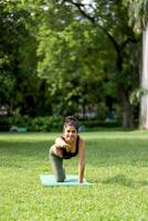 Front View Of Nice Hot Woman Performing Cow Cat Pose In Park photo