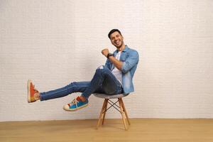 A Smart Man Is Smiling While Sitting On A Stool And Posing photo