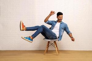 A Young Handsome Man Is Sitting On A Stool And Having Fun photo