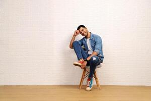 A Happy Guy In Casual Clothes Sitting On A Chair And Posing photo