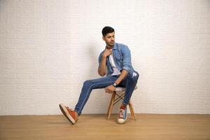 Charming Guy Is Posing While Sitting On Chair photo