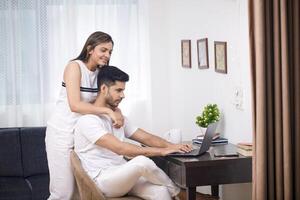 Picture Of Sexy Couple Sitting In Living Area Husband Working On Laptop And Wife Standing Behind Him photo