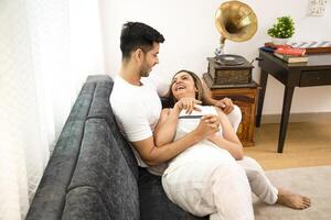 Good Couple Where Woman Lying On Man's Lap While Talking With Him On Sofa At Home photo