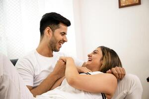 Brunette Couple Smiling And Looking At Each Other While Holding Hands photo