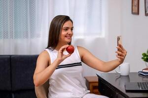 Pretty Mature Lady In White Outfit Holding Apple In Hand While Chat photo