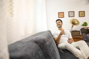 Young Handsome Man Sitting On Sofa And Drinking Tea photo