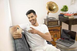 Attractive Man Smiling Watching Clip On Mobile Phone While Drinking Coffee photo