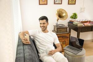 Hot Guy Scrolling On Mobile Phone While Drinking Coffee photo