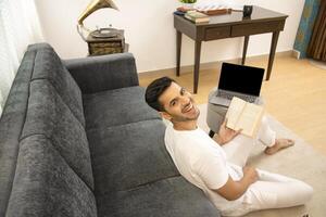 más hermoso chico sonriente mientras torneado espalda mientras participación libro en mano foto