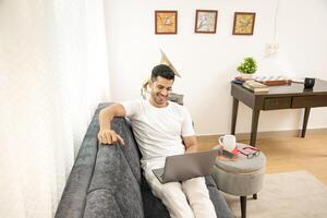 Most Sexy Man Working On Laptop While Sitting On Sofa photo