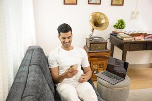 Sexiest Man Holding Mug In Hand While Scrolling On Mobile Phone photo