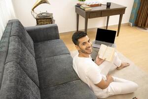 Handsome Guy In White Outfit Smiling And Turning Back Looking At Camera While Holding Book In Hand photo