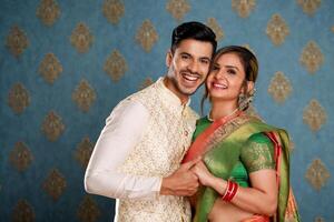 A Newly Married Couple In Traditional Outfit Holds Hands And Smile While Giving A Pose To The Camera photo