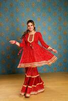 Traditional Indian Lady In Red Sharara Suit Posing In Front Of Camera photo