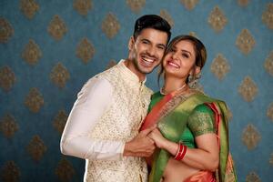 Picture Of An Adorable Couple Wearing Traditional Indian Attire Holding A Plate Of Ladoos In Their Hands And Smile photo