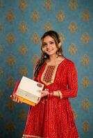 indio linda mujer en un rojo traje participación diwali regalos en su manos foto