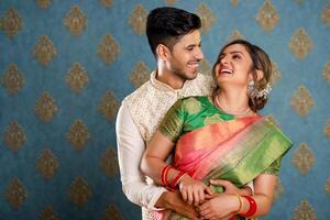 sonriente adorable Pareja vestido en tradicional indio atuendo abrazando cada otro en frente de el cámara foto