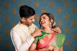 Stock Image Of An Indian Couple Dressed In Traditional Attire, With The Man Presenting The Woman With A Diamond Necklace photo