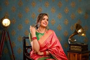 Top Female Model Seated On Chair And Posing For The Camera While Wearing A Saree photo