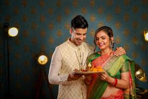 imagen de un dulce Pareja vistiendo tradicional indio atuendo durante diwali festival participación puja plato en su manos foto