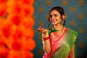 Smiling Beautiful Housewife In Saree Holding Diya During Diwali Festival photo