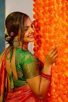 Beautiful Mature Woman In Saree During The Diwali Festival Standing Next To The Florally Decorated Wall photo