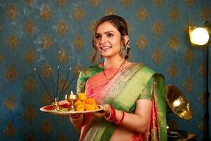 A Gorgeous Girl In Saree While Celebrating Diwali Holding A Puja Plate photo