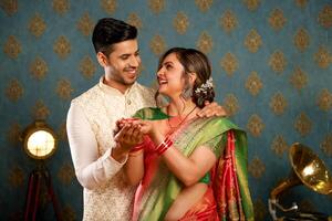 Indian Couple In Traditional Outfit Holding Diya And Looking At Each Other photo