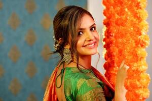 A Slim Woman In Saree Standing Next To The Flower-Decorated Wall photo