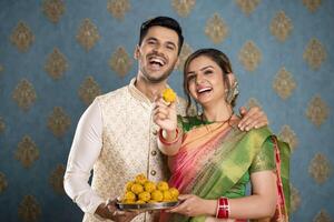 Smiling Asian Young Couple Showing Laddu In Front Of Camera. photo