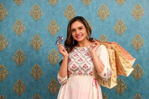 Beautiful Model Laughing While Holding Shopping Bags And Displaying Debit Card On Camera Screen photo
