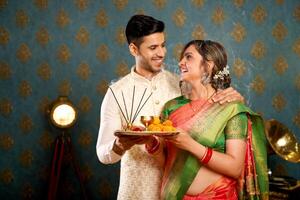 Great Couple In Traditional Indian Attire Holding Pooja Plate In Their Hands While Looking At One Another photo