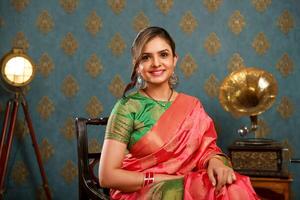 Beautiful Female In Saree Sitting On Chair WHile Posing In Front Of Camera photo