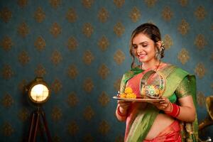 un linda esposa participación pooja plato a el karva chauth festival en tradicional indio atuendo foto