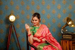 Young Lady Wearing Saree Sitting On A Chair And Posing In Front Of The Camera photo