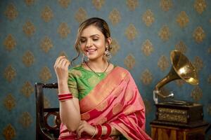 A Young Woman Model Posing While Seated On A Chair In Saree photo