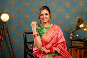 A Beautiful Woman In Saree Sits On A Chair While Posing In Front Of The Camera photo