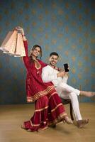 A Young Couple Enjoying Themselves While Holding Shopping Bags And Sitting On A Chair In Front Of The Camera photo