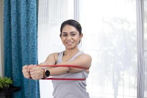 Lady Stretching Resistance Band While Posing In Front Of Camera photo