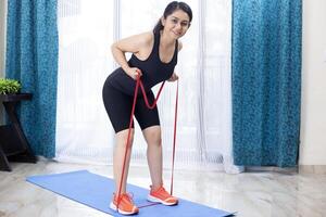 Indian Trainer Doing Tricep Kickbacks Resistance Band Exercise photo